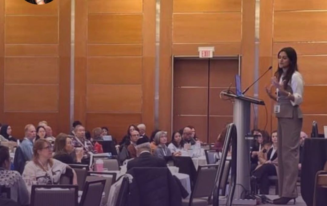 Dr. Fallon Patel speaking at a podium to a full room